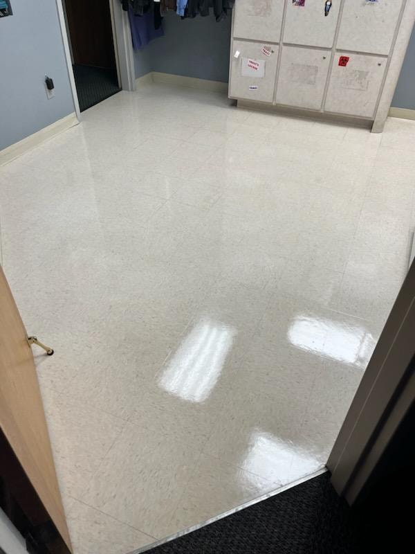 Medical facility locker room floor after stripping and waxing — bright, polished VCT tile