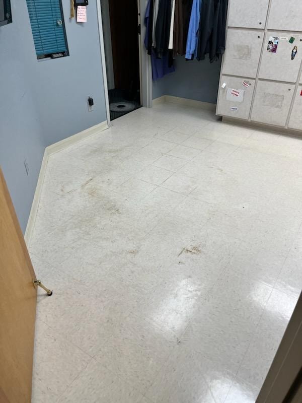 Medical facility locker room floor before cleaning — stained and dull VCT tile